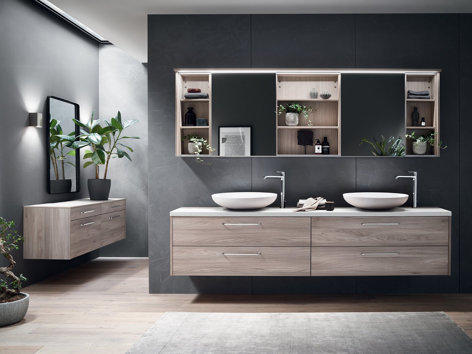 Meuble de salle de bain en bois clair à deux vasques, avec tiroirs et rangements muraux.
